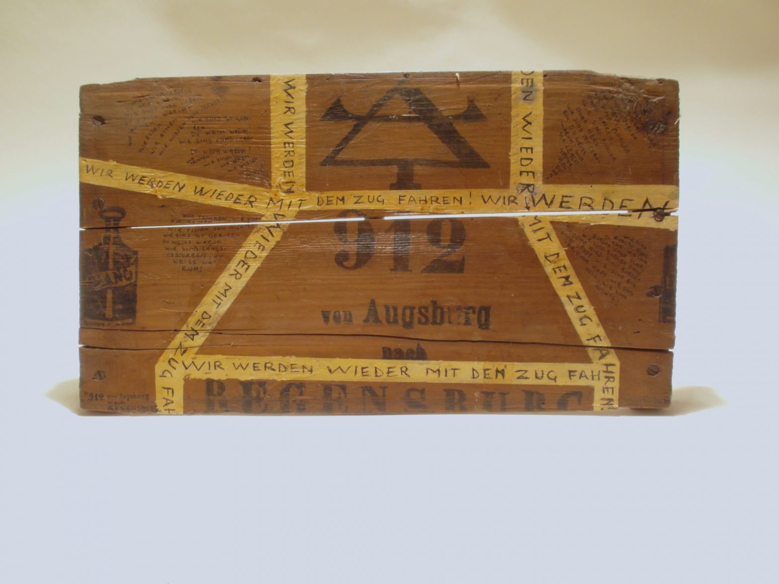 Found wood board. Printed with text (= title). Several handwritten texts on the board.