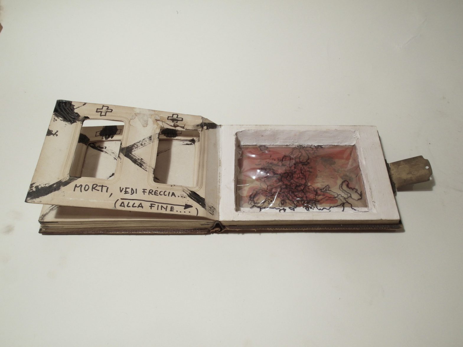 Large square cutted out of half book core. Plastic foil inside the cut out. Handdrawn map of europe on the plastic. Handwritten message on left side.