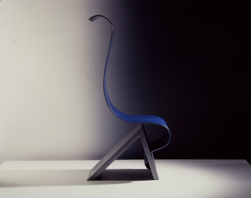 Chair consists of wave-formed sitting area mounted on the edge of a triangular base.