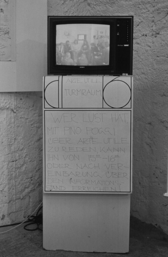 TV stands on a column. Poster with handwritten text hangs on the column.